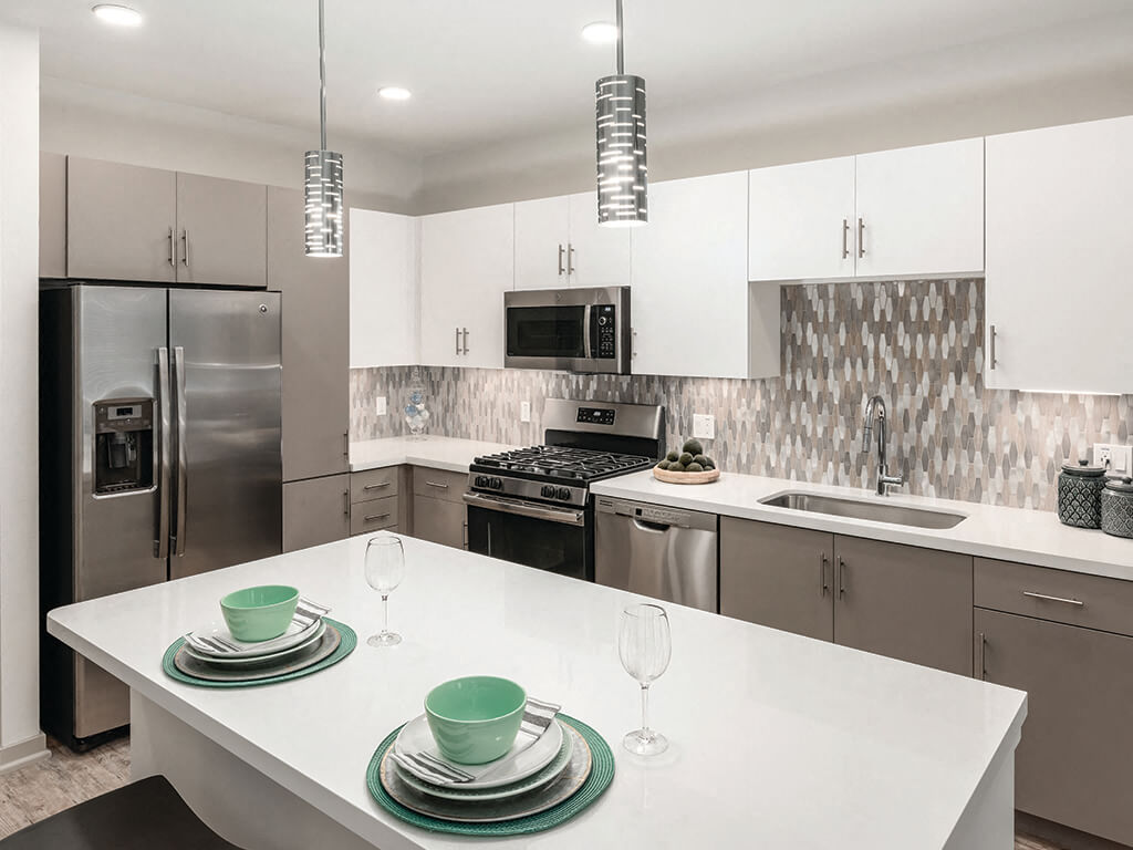 A white, modern kitchen with an island at the Norte Town Lake Apartments in Tempe, Arizona.